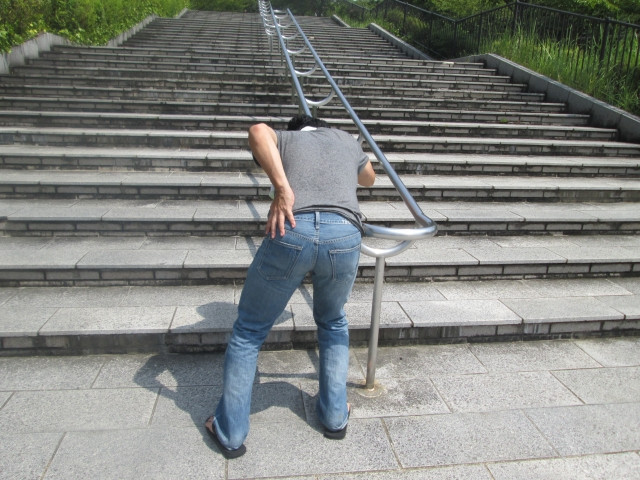 腰の痛みで階段が登れない男性の写真
